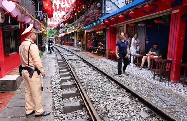 Officer and people near a railway surrounded by colorful buildings and decorations.